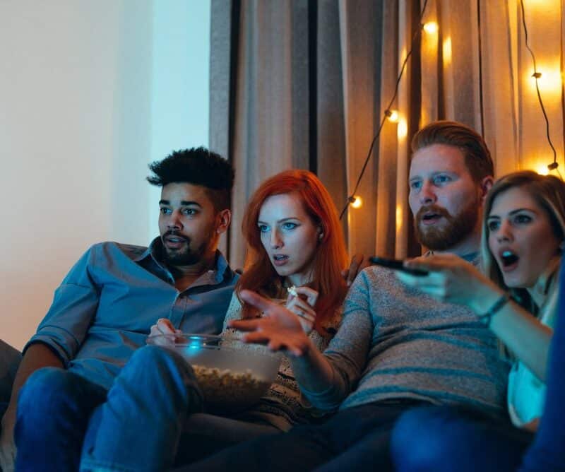 Four friends watching a scary movie on the couch.
